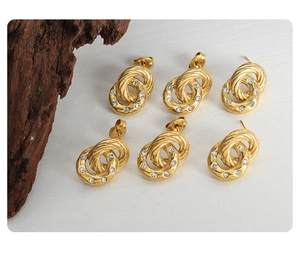 Detail of 18K gold plated double loop earrings with zircon inlay and twisted metal texture
