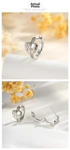 Macro detail of silver heart earrings with cross relief and micro-set zirconia stones