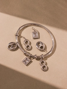Detail of coffee bean and square zircon charms on an 18k gold plated stainless steel bangle