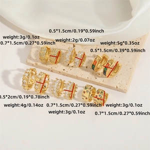 Collection of six gold-plated hollow hoop earrings with cubic zirconia on stone background