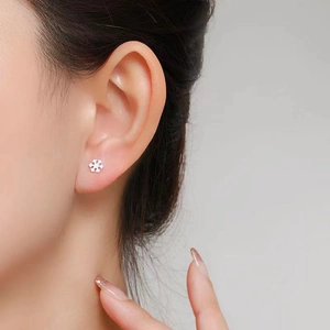 Close-up of elegant snowflake-shaped silver stud earring worn on a female ear