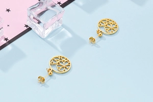 Detailed close-up of gold hollow flower earrings with rhinestones on a blue background