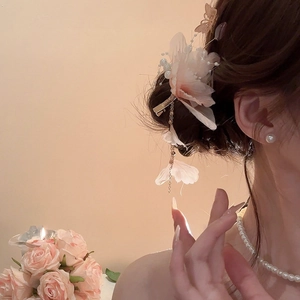 Dettaglio della clip per capelli a fiore rosa con perle e nappa dorata sui capelli