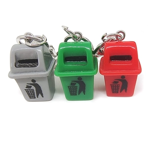 Miniature trash can keychains in grey, green, and red colors on a white background