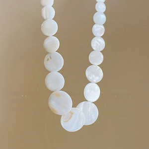 Macro shot of white mother of pearl shell necklace with gradient flat round beads