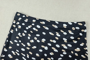 Detailed close-up of elastic waist band on black trousers with polka dot pattern