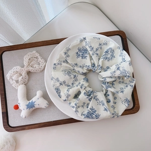 Detail of floral cotton scrunchie with blue flower pattern on creamy white fabric