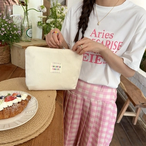 Close-up of textured cream corduroy makeup bag in a warm lifestyle setting