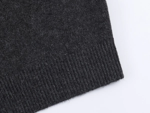 Close-up of charcoal gray knit cardigan showing fine texture and ribbed hem detail