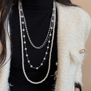 Detail of elegant multi-layered faux pearl necklace with silver chains on a model