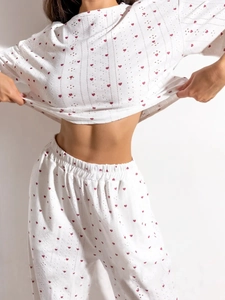Détail du haut et pantalon blancs en tissu ajouré avec motifs de petits cœurs rouges vifs