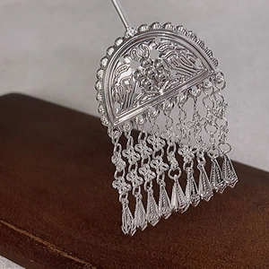 Close-up of vintage silver hair stick with ornate hollow bird pattern and hanging tassels