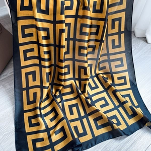 Detail of lightweight scarf featuring a classic black and gold Greek key pattern