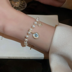 Close-up of pearl flower charm bracelet with blue gemstone on a vintage book