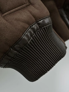Macro detail of brown faux suede jacket sleeve with faux leather cuff and fine stitching
