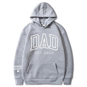 Sweat à capuche gris avec imprimé DAD EST 2024 et détail cœur sur la manche, fond blanc
