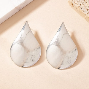 Close-up of silver teardrop earrings featuring a refined brushed metal texture surface