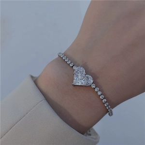 Close-up of a silver heart-shaped pendant bracelet with cubic zirconia on a woman wrist