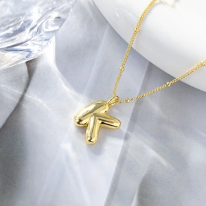 Vista macro di una collana con ciondolo a lettera K in oro 18K dal design a palloncino