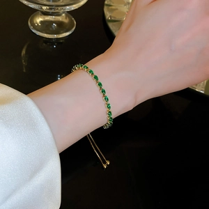 Detailed close-up of adjustable gold bracelet with green teardrop zircon gemstones