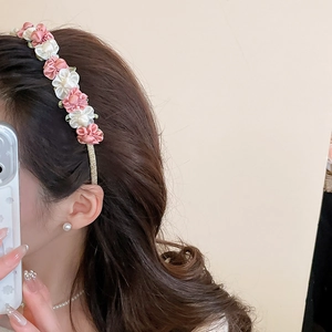 Detail of pink and white satin fabric flowers on elegant thin gold metal headband