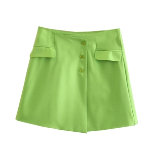 Detail of bright green mini skirt featuring decorative front buttons and flap pockets