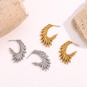 Detailed macro view of gold and silver textured wing-shaped earrings on stone