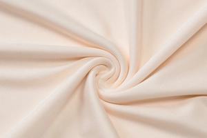 Close-up of cream knit fabric texture with elegant spiral draping for a summer dress
