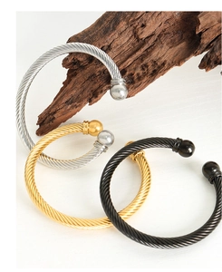 Vista dettagliata di tre braccialetti a cavo intrecciato in argento, oro e nero su base