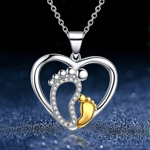 Detailed view of silver and gold baby feet pendant inside a heart-shaped necklace frame