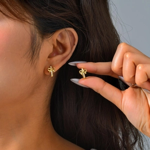 Elegant gold bow earrings with white zircons shown on model for a stylish look