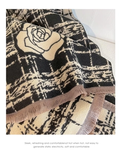 Close-up of beige cashmere scarf with rose pattern, plaid design and tassel fringe details