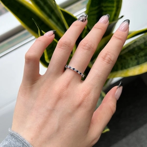 Detailed view of S925 silver eternity ring with blue sapphires and white diamonds on finger