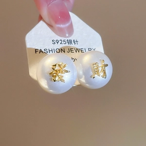 Détail macro de boucles d'oreilles en argent S925 avec perles et caractères chinois dorés