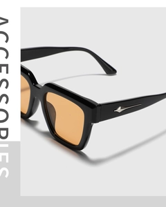 Detail of square black sunglasses with amber lenses and silver arrow metal rivets