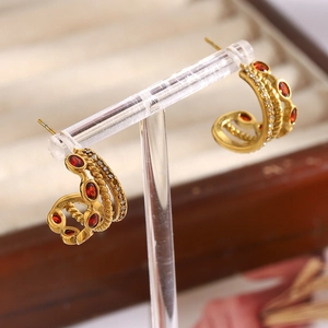 Macro detail of 18K gold-plated triple hoop earrings with red zircon and crystal stones