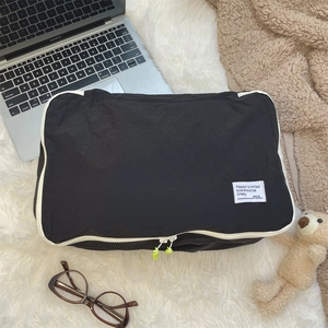 Close-up of black travel organizer with yellow zippers on a white plush rug background