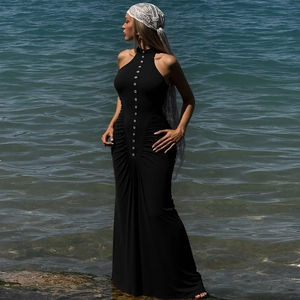 Primer plano de botones plateados y detalles fruncidos en un vestido negro con cuello halter
