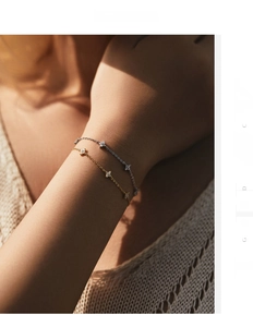 Detail of silver and gold four-leaf clover bracelets featuring micro-inlay on elegant chains