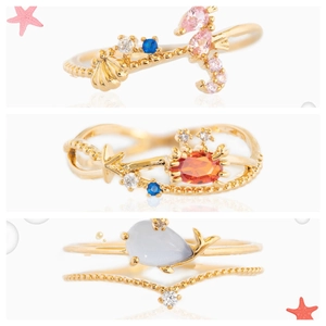 Macro detail of gold sea animal rings with colorful zircons in crab and seahorse shapes