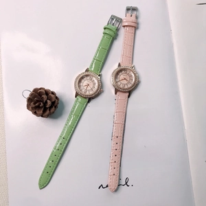 Close-up of pink and green quartz watches with rhinestone bezels and leather straps
