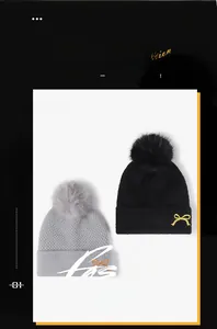 Detailansicht der Strickmützen mit Bommel und goldenem Schleifenstickerei in Schwarz und Grau