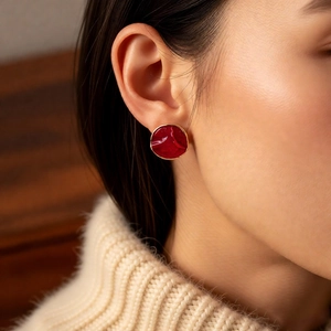 Close-up of vintage style red enamel round stud earring with gold-plated wavy edges