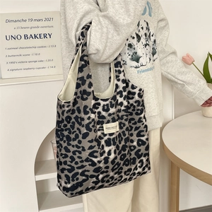 Close-up of leopard print canvas tote bag with white woven label on model's shoulder