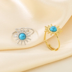 Detail of sunflower open rings in gold and silver finish with turquoise stone on silk fabric