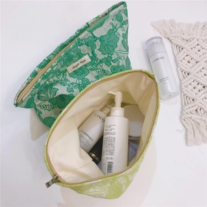 Detailed close-up of green floral jacquard fabric and simple wish label on the cosmetic bag