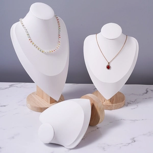 White leather and beech wood necklace bust set for jewelry display on marble surface