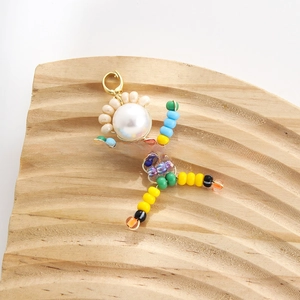 Detailed shot of handmade colorful beaded figure pendant with pearl head on wooden base