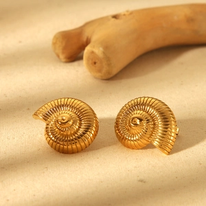 Macro shot of 18k gold plated conch shell stud earrings on natural wood texture