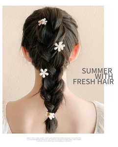 Detail of four floral pearl hair clips styled in a braided half-up hairstyle for women